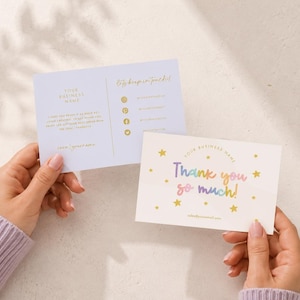 Puede incluir: Dos tarjetas de visita rectangulares con fondo blanco. Una tarjeta presenta texto dorado que dice "YOUR BUSINESS NAME" y "Let's keep in touch!" con iconos de redes sociales. La otra muestra "Thank you so much!" en degradado arcoíris con estrellas doradas.