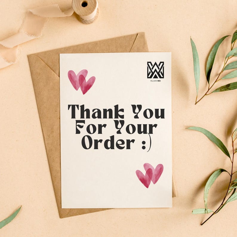Puede incluir: Una tarjeta color crema con el texto "Thank You For Your Order :)" en negrita negra, acompa&ntilde;ada de dos conjuntos de corazones rosas superpuestos. La tarjeta est&aacute; colocada sobre un sobre marr&oacute;n, con una bobina de cinta y vegetaci&oacute;n en el fondo.