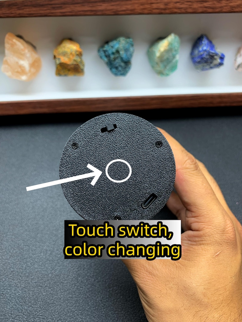 May include: A circular black textured base featuring a touch switch for colour changing, a small power toggle, and a USB-C charging port. A white arrow points to the circular touch sensor area, with text reading Touch switch, colour changing.