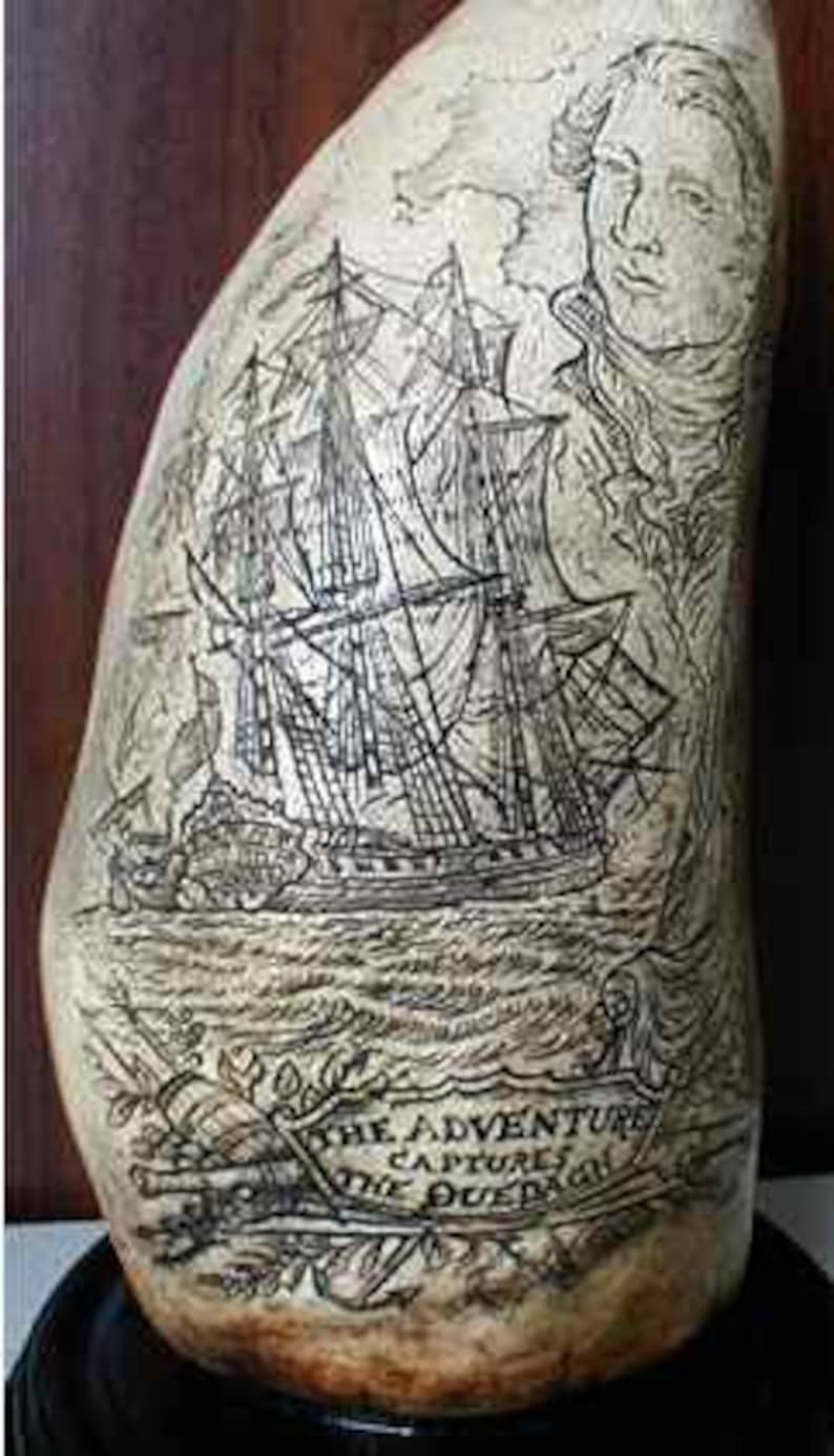 Op de afbeelding: Een gegraveerde walvistand met een gedetailleerde illustratie van een schip, een portret van een man en de tekst "The Adventure Captures the Duepa."