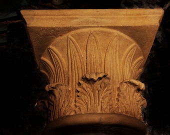 May include: A close-up of a decorative stone column with intricate carvings. The column is made of a light brown stone and has a detailed design of leaves and flowers.