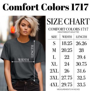 Op de afbeelding: Een donkergrijs Comfort Colors 1717 heavyweight volwassen T-shirt. De afbeelding bevat een maattabel met afmetingen in inches voor maten S tot en met 4XL. De tabel toont breedte- en lengtematen voor elke maat.