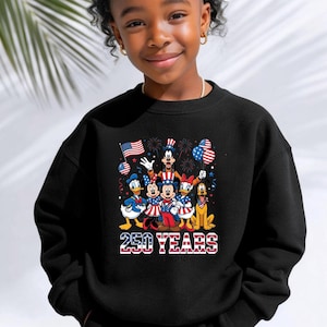 May include: A black long-sleeve sweatshirt featuring a graphic print of cartoon characters dressed in red, white, and blue patriotic attire. The design includes the text 250 YEARS with a stars and stripes pattern and fireworks in the background.