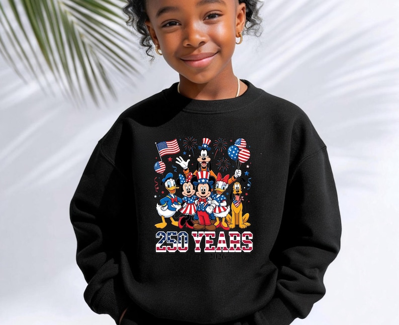 May include: A black long-sleeve sweatshirt featuring a graphic print of cartoon characters dressed in red, white, and blue patriotic attire. The design includes the text 250 YEARS with a stars and stripes pattern and fireworks in the background.