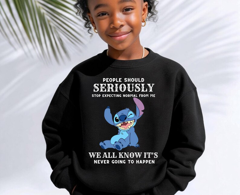 May include: A black long-sleeve sweatshirt featuring a graphic of the blue character Stitch from Lilo and Stitch. The text reads: PEOPLE SHOULD SERIOUSLY STOP EXPECTING NORMAL FROM ME WE ALL KNOW IT'S NEVER GOING TO HAPPEN in white lettering.