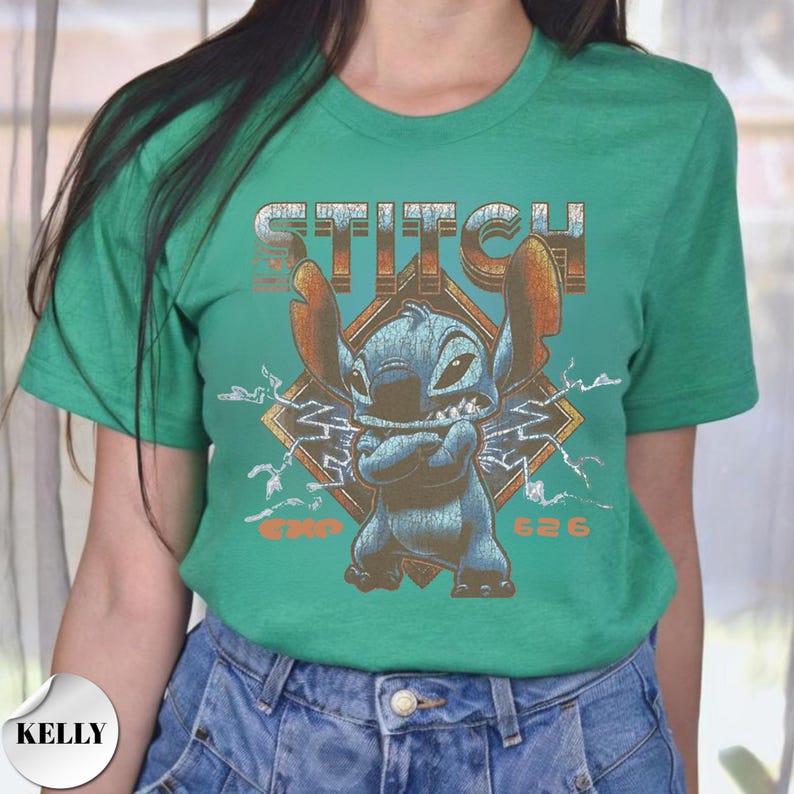 May include: A bright green short-sleeve t-shirt featuring a graphic of the blue character Stitch with arms crossed. The design includes the text STITCH at the top, lightning bolts in the background, and the text EXP 626 at the bottom in orange.