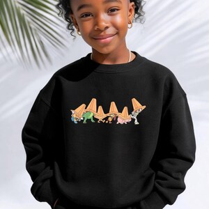 Op de afbeelding: Zwart sweatshirt met een cartoonafbeelding van personages met oranje verkeerskegels. De afbeelding staat op de borst. Het sweatshirt is gemaakt van een zacht materiaal en heeft een ronde hals.