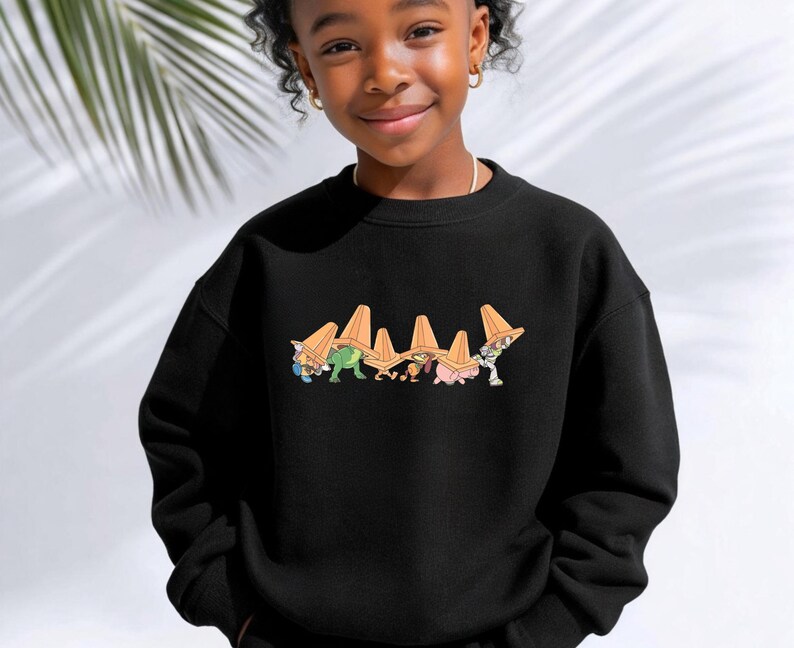 Op de afbeelding: Zwart sweatshirt met een cartoonafbeelding van personages met oranje verkeerskegels. De afbeelding staat op de borst. Het sweatshirt is gemaakt van een zacht materiaal en heeft een ronde hals.