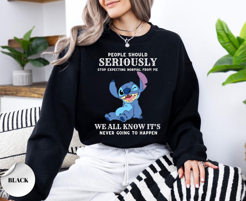 May include: A black crewneck sweatshirt featuring a graphic of the blue character Stitch from Lilo & Stitch. The text reads: PEOPLE SHOULD SERIOUSLY STOP EXPECTING NORMAL FROM ME WE ALL KNOW IT'S NEVER GOING TO HAPPEN in white lettering.