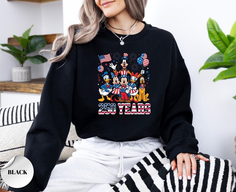 May include: A black long-sleeve crewneck sweatshirt featuring a graphic print of cartoon characters dressed in patriotic red, white, and blue clothing. The design includes the text 250 YEARS in a flag-patterned font, surrounded by balloons and fireworks.