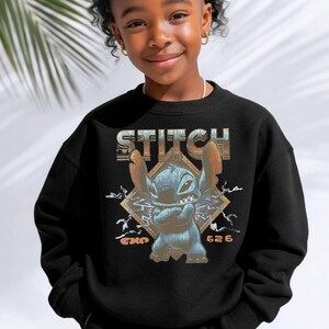 May include: A black crewneck sweatshirt featuring a graphic print of the character Stitch with arms crossed. The design includes the text STITCH at the top, EXP 626 at the bottom, and a diamond-shaped background with lightning bolt accents.