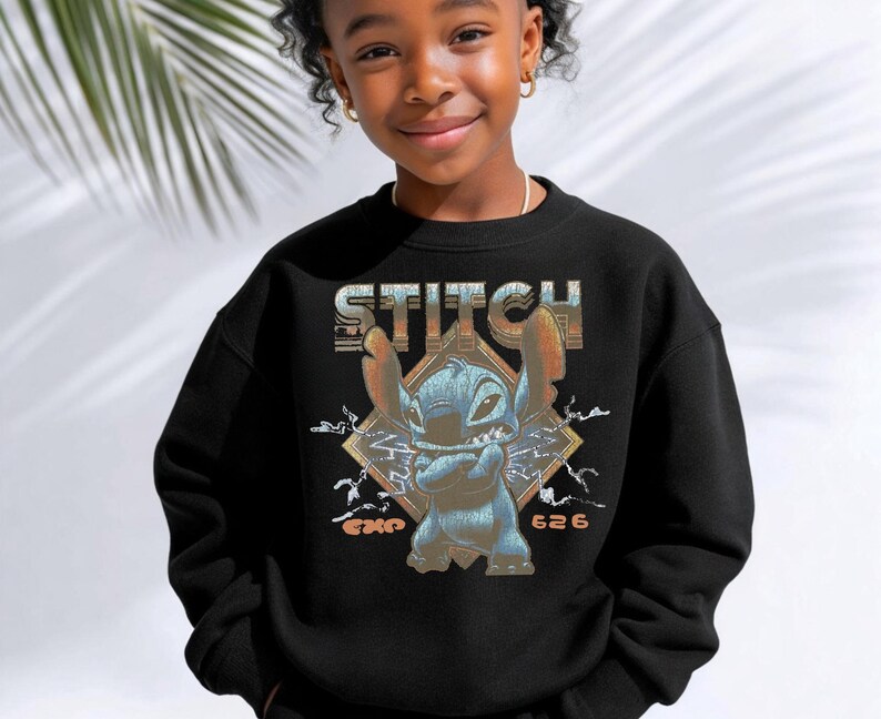 May include: A black crewneck sweatshirt featuring a graphic print of the character Stitch with arms crossed. The design includes the text STITCH at the top, EXP 626 at the bottom, and a diamond-shaped background with lightning bolt accents.