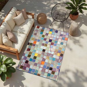 May include: Rectangular outdoor rug with a colourful mosaic tile pattern. The rug features a variety of square tiles in shades of blue, green, yellow, orange, and purple. The rug is placed on a patio with outdoor furniture.