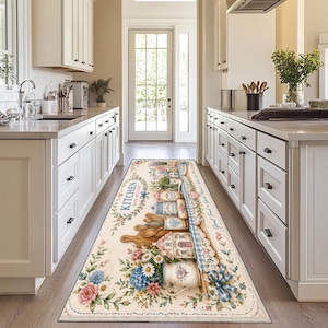 May include: A rectangular kitchen runner rug featuring a cream background with a printed design of wooden cutting boards, kitchen canisters, rolling pins, and floral arrangements. The text KITCHEN MADE WITH LOVE is printed in blue script.
