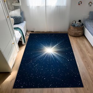 May include: A rectangular rug with a dark blue background and a bright white starburst design. The rug features a pattern of small white dots, resembling stars. This rug is suitable for a bedroom or living room.