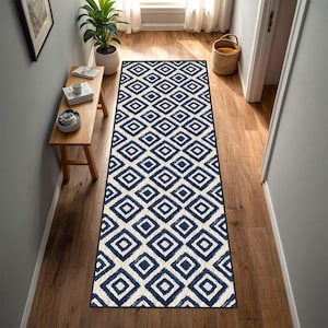 May include: A long rectangular runner rug featuring a repeating geometric pattern of dark blue diamonds on a cream-colored background. The rug has a thin dark border and is positioned centrally on a wooden floor in a hallway setting.