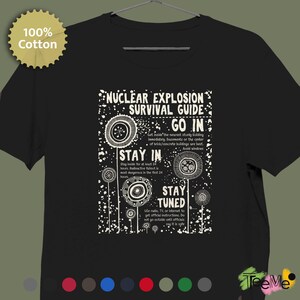 Könnte beinhalten: Schwarzes Baumwoll-T-Shirt mit weißer Grafik, die "NUCLEAR EXPLOSION SURVIVAL GUIDE" lautet. Das Design enthält Anweisungen und stilisierte Illustrationen. Ein rundes 100% Baumwoll-Etikett befindet sich in der oberen linken Ecke.