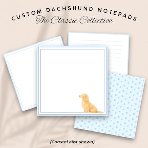 May include: Custom Dachshund notepads from The Classic Collection in Coastal Mist. The set includes square paper sheets with a light blue border and a small illustration of a light brown dog, lined paper, and paper with a light blue paw print pattern.