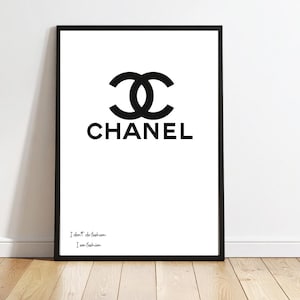 Peut inclure: Tableau encadré noir avec le logo Chanel noir sur fond blanc. Le mot "CHANEL" est en dessous du logo. Le bas de l'art contient le texte "I don't do fashion. I am fashion."