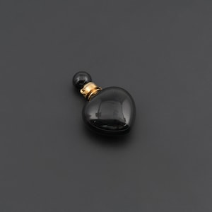 May include: A heart-shaped black stone pendant with a polished, glossy finish. The top of the heart features a gold-toned metal cap with a small circular loop for attachment, topped with a smooth, round black bead accent.