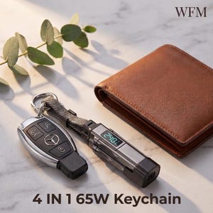 May include: A 4 in 1 65W keychain featuring a digital display showing 240, attached to a Mercedes car key fob with a grey fabric strap. The device is positioned next to a brown leather wallet. The text WFM is visible in the top right corner.
