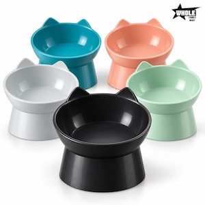 May include: Five elevated pet bowls with cat-ear shaped rims, arranged in a group. The bowls come in solid colors: black, white, teal, peach, and mint green. Each bowl features a wide, stable base and a smooth, rounded interior surface.