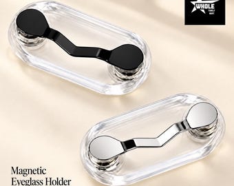 May include: Two magnetic eyeglass holders with clear oval bases. One holder features a black metal clip, and the other has a silver metal clip. The text "Magnetic Eyeglass Holder Eyewear within reach." and a "WHOLE FAMILY MART" logo are visible.