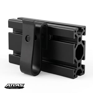Op de afbeelding: Zwart aluminium profiel met een zwarte clip bevestigd. De extrusie heeft een reeks parallelle kanalen en een centrale zeshoekige opening. De clip is gebogen en heeft een enkel montagegat. Het logo "ATLAS DESIGN" is zichtbaar.