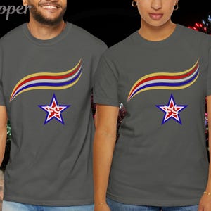 May include: Two gray t-shirts with a star and ribbon design. The star is blue with a red and white outline and a red design in the center. The ribbon is yellow, red, and blue. The shirts are short-sleeved.