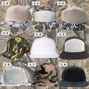 Op de afbeelding: Een verzameling baseballpetten met platte klep in verschillende kleuren en patronen. Stijlen zijn effen kleuren, camouflage en mesh-ruggen. Sommige petten hebben een wit voorpaneel, terwijl andere een patroon op de klep hebben.