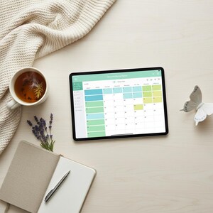May include: A flat lay image featuring a tablet displaying a calendar, a cup of tea, a notebook with a pen, a decorative butterfly, and a knitted blanket. The calendar has a green header and blue and yellow highlighted dates. The tea cup is white.