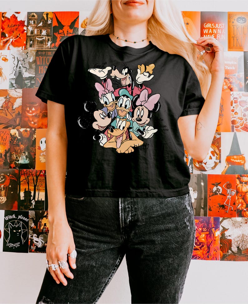 May include: Black t-shirt featuring a colorful graphic of Disney characters including Mickey Mouse, Minnie Mouse, Donald Duck, Daisy Duck, Goofy, and Pluto. The shirt is a classic crew neck style.