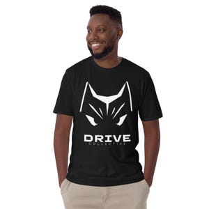 以下が含まれることがあります： 白い動物の顔のグラフィックと「DRIVE COLLECTIVE」の文字が入った黒いTシャツ。Tシャツは柔らかい素材でできており、半袖です。