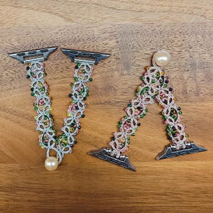 May include: Two beaded watch straps with silver connectors. The straps are made of a light-coloured thread and decorated with colourful beads in green, pink, and yellow. Each strap has a pearl accent.