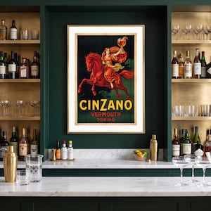 Può includere: Un poster incorniciato in stile vintage raffigurante una persona in abito rosso a cavallo di un cavallo rosso mentre tiene in mano un bicchiere di liquido ambrato. Il testo recita CINZANO VERMOUTH TORINO in lettere gialle e rosse.