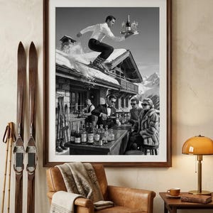 May include: Black and white framed print depicting a skier leaping over a snowy roof while balancing a tray of champagne and glasses. A bar scene with people in formal attire is visible below. Vintage skis and a leather chair are in the foreground.