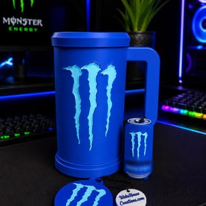 May include: A blue cylindrical mug with a large handle featuring a light blue Monster Energy claw logo, a smaller matching blue beverage can replica, and a round blue coaster with the same logo and a white tag reading WebsHouse Creations.com.
