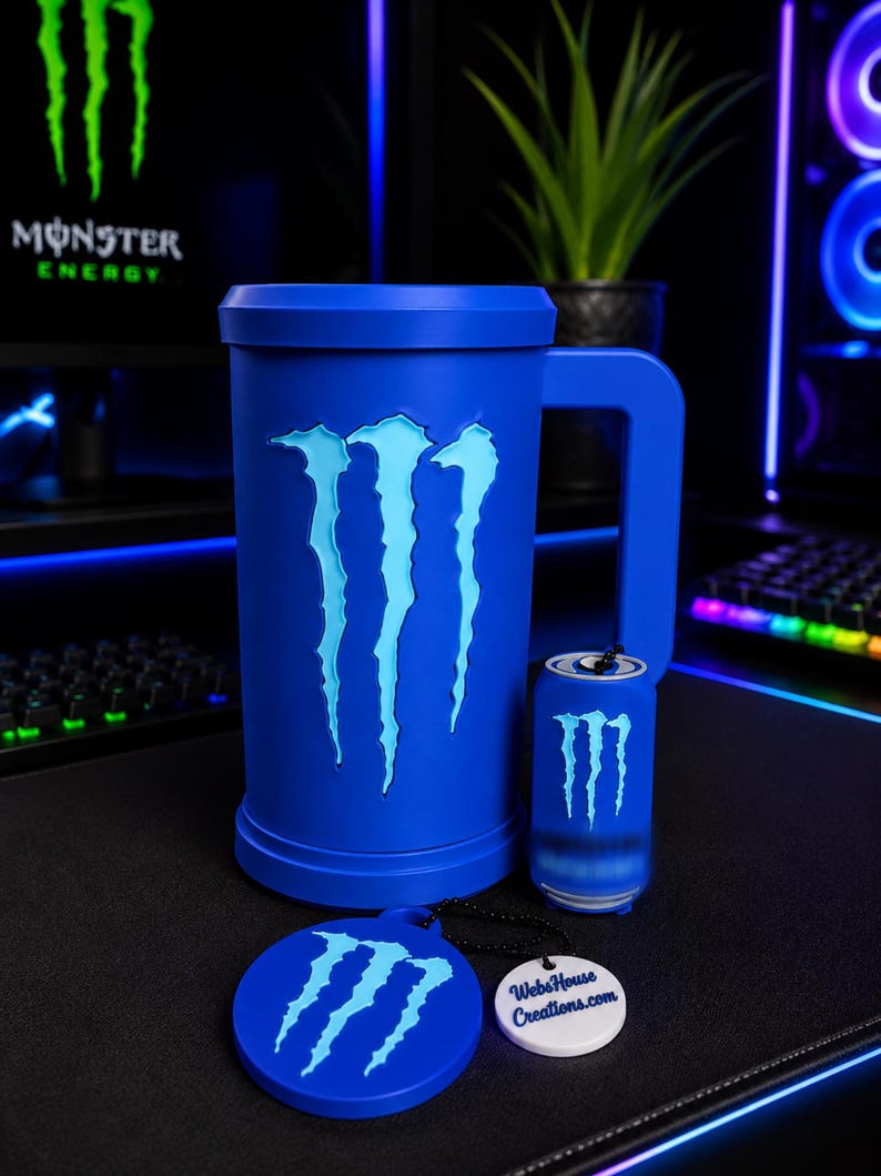 May include: A blue cylindrical mug with a large handle featuring a light blue Monster Energy claw logo, a smaller matching blue beverage can replica, and a round blue coaster with the same logo and a white tag reading WebsHouse Creations.com.