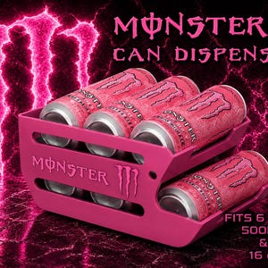 May include: A pink Monster can dispenser featuring the Monster logo and text. The unit holds six cans, with text stating it fits 500ml and 16 oz cans. The dispenser has two tiers with horizontal slots, displaying pink Monster energy drink cans inside.