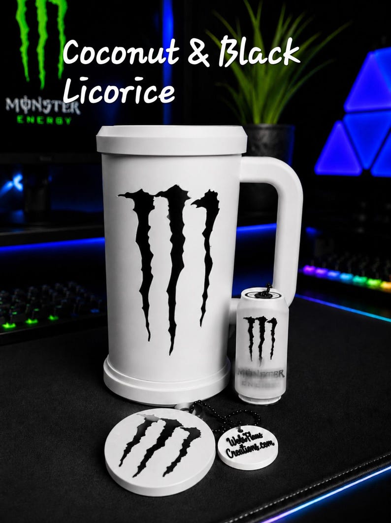 May include: A white mug featuring a large black Monster Energy logo, accompanied by a miniature white can replica and a round white keychain with the same logo and the text WebPlane Creations.com, labeled Coconut & Black Licorice.