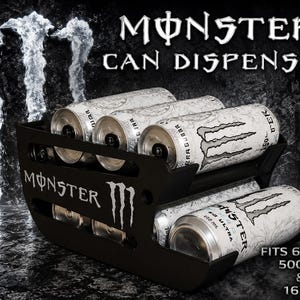 May include: A black Monster can dispenser featuring the Monster logo and text. The unit holds six cans, with white Monster Ultra cans visible inside. Text on the dispenser reads Monster Can Dispenser, Fits 6 Cans, 500ml & 16 oz. The design is open-sided.