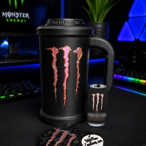 Può includere: Una tazza nera opaca con un grande logo iridescente Monster Energy e la scritta L-CARNITINE sul coperchio. Include un piccolo portachiavi abbinato a forma di lattina e un portachiavi circolare nero testurizzato con lo stesso logo e un'etichetta.