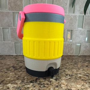 May include: A colorful water cooler with a pink lid and handle, gray band, and yellow body. The cooler has a white base, black spigot, and is designed for outdoor use. The cooler is made of plastic.