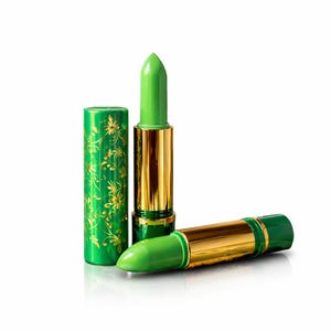 May include: Two lipstick tubes with bright green pigment. One tube stands upright with its cap removed, revealing the green lipstick. The other tube lies horizontally. Both feature a metallic gold center and green casing with gold floral patterns.