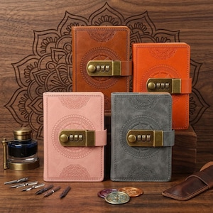 May include: Four leather journals in shades of brown, orange, pink, and gray, each with a combination lock and embossed mandala design. The journals are closed with a strap and buckle. The background is a wooden surface.