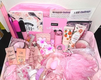 Puede incluir: Una caja de regalo rosa llena de artículos de belleza y papelería. Incluye bálsamo labial, crema de manos, maquillaje, lápices, un cuaderno y flores decorativas. La caja también contiene pequeñas bolsas de regalo y una esponja rosa.