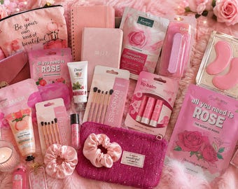 Puede incluir: Una colección de artículos de belleza y cuidado personal en tonos rosa que incluye un neceser con el texto Be your own kind of beautiful, una agenda 2027, mascarillas de rosas, bálsamos labiales, brochas, coleteros, crema Dove y parches.
