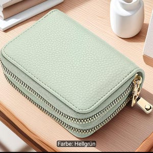 Puede incluir: Una cartera rectangular de color verde menta con una superficie texturizada y esquinas redondeadas. La cartera cuenta con dos compartimentos con cremalleras met&aacute;licas en tono dorado y tiradores a juego para un cierre seguro.