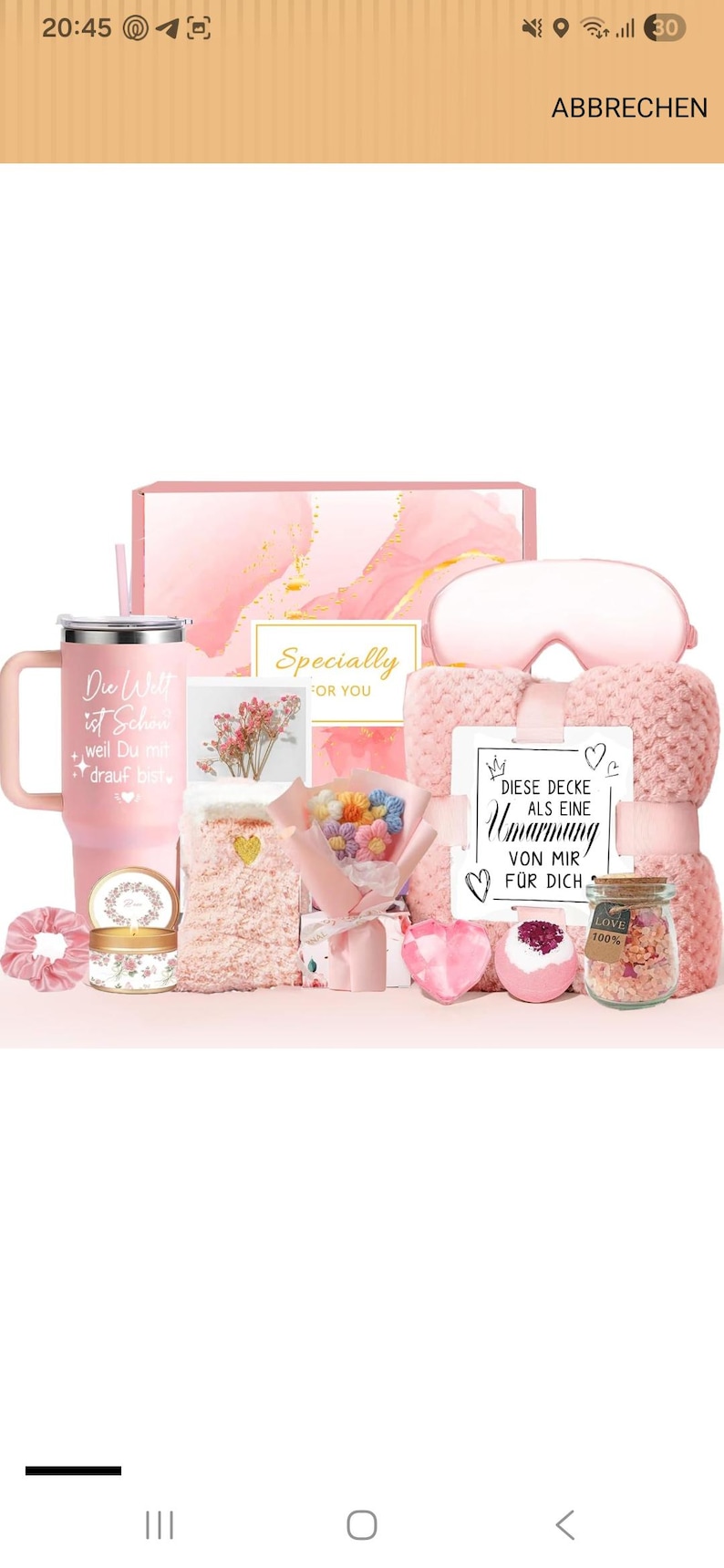 Puede incluir: Un set de regalo rosa que incluye un vaso con texto en alem&aacute;n, una manta de felpa con la etiqueta DIESE DECKE ALS EINE Umarmung VON MIR F&Uuml;R DICH, un antifaz, un ramo de flores de ganchillo, una vela, un coletero y un frasco de sales de ba&ntilde;o.