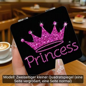 Puede incluir: Un espejo de bolsillo cuadrado con fondo negro que presenta un gr&aacute;fico de corona rosa brillante y la palabra Princess en letras rosas. El espejo tiene una bisagra de metal plateado y es un modelo de doble cara con un lado de aumento.
